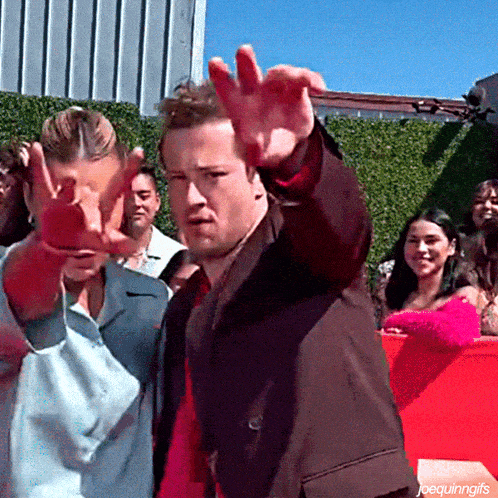 a man in a suit waves his hand in front of a crowd of people