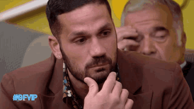 a man with a beard is sitting in front of another man with #gfvip written on the bottom right