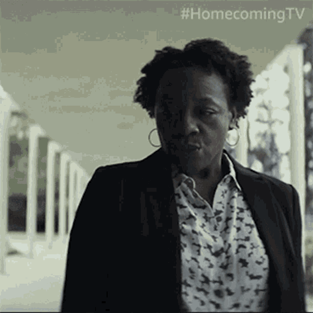 a woman in a suit is walking down a hallway with #homecoming tv written on the ceiling
