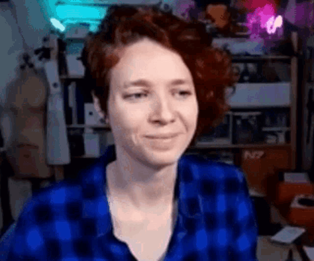 a woman with red hair and a blue plaid shirt is smiling .