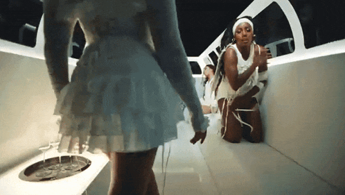 a woman in a white dress is kneeling down in front of a sink .