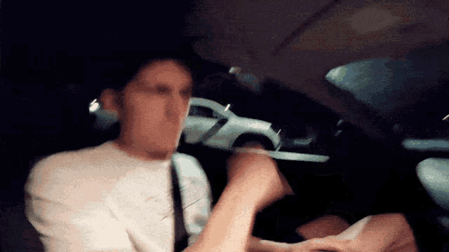 a blurry photo of a man in a car with a white car in the background