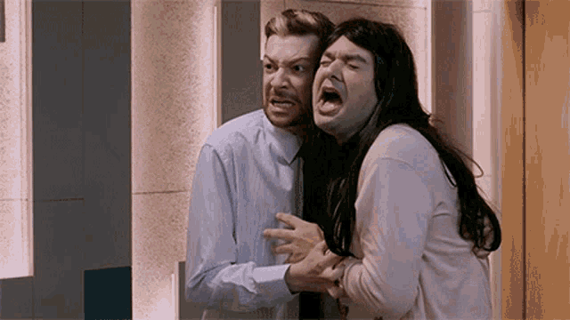 a man and a woman are making funny faces while standing next to each other in a room .