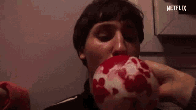 a man is blowing up a red and white ball with hearts on it .