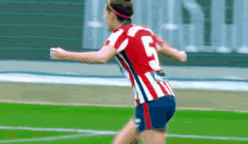 a female soccer player wearing a red and white striped jersey with the number 5 on it is running on the field .