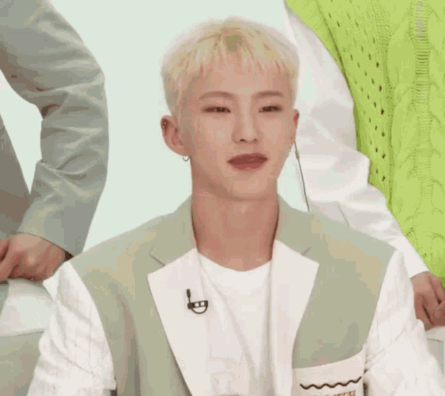 a man in a green vest makes a heart with his hands