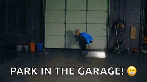 a man in a blue shirt is squatting in front of a garage door with the words park in the garage