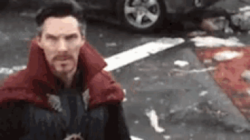 a man in a red cape is standing in a parking lot .
