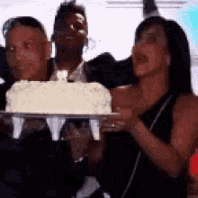 a woman in a black dress is holding a cake in her hands .