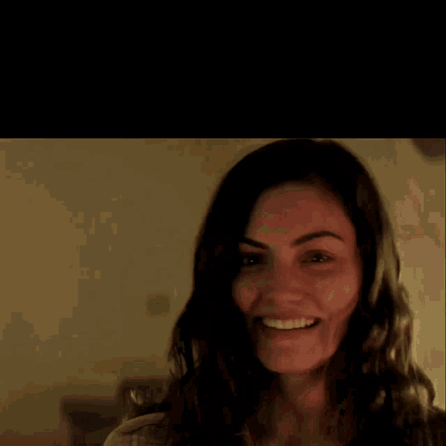 a close up of a woman 's face smiling in a dark room