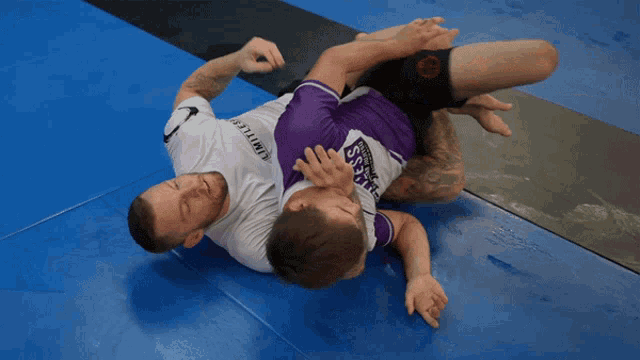 a man wearing a purple shirt that says samurai is wrestling another man
