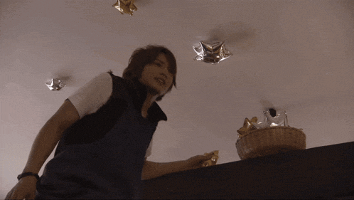 a person is looking up at a ceiling with a basket of gold stars in the background