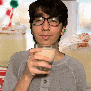 a man wearing glasses holds a glass of milk