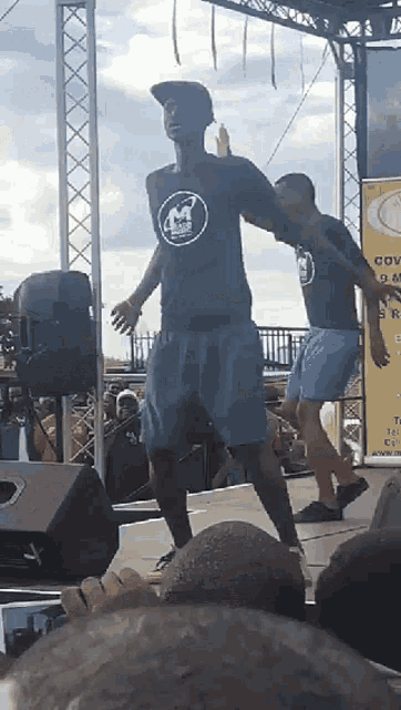 a man wearing a shirt with the letter m on it is dancing on a stage