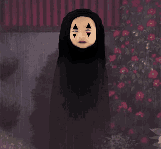 a child in a black hooded cape with triangles painted on his face
