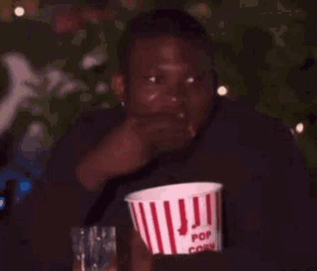 a man is sitting at a table eating popcorn .