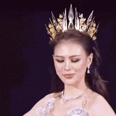 a woman wearing a tiara and a necklace looks down