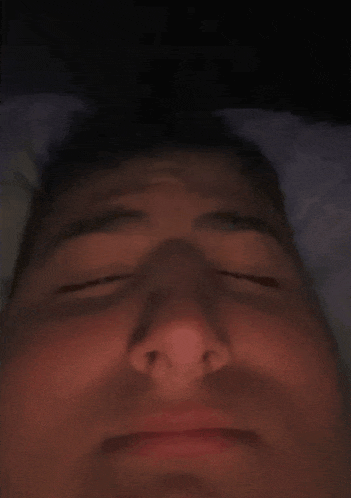 a close up of a man 's face with his eyes closed in a dark room .