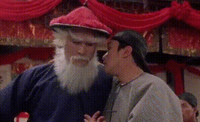 a man with a beard and a hat is standing next to another man with a beard .