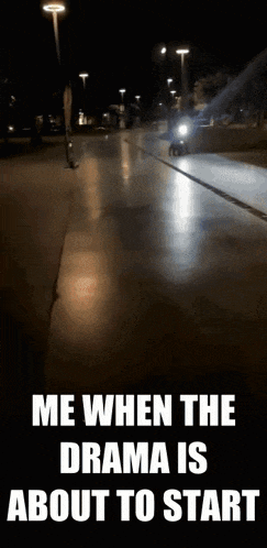 a motorcycle is driving down a street at night with a caption that says me when the drama is about to start .