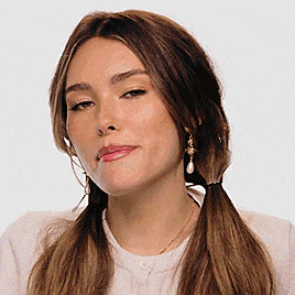 a woman wearing a white shirt and earrings is making a face .