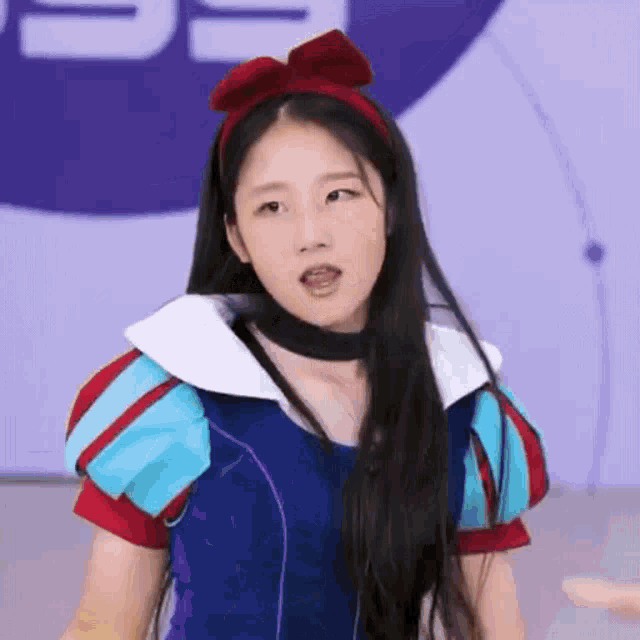 a girl in a snow white costume is making a funny face while wearing a headband .