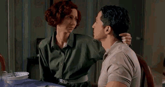 a man and a woman are sitting at a table and the man is touching the woman 's arm .