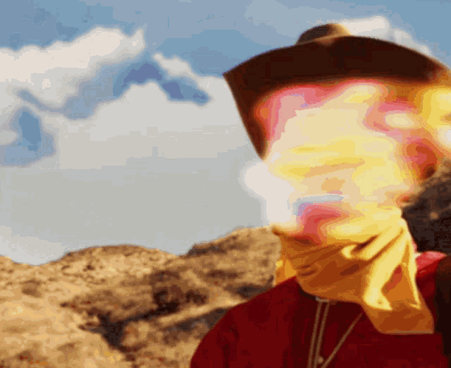 a person wearing a cowboy hat and a yellow bandana around their neck