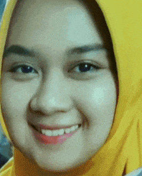 a close up of a woman wearing a yellow hijab and smiling .