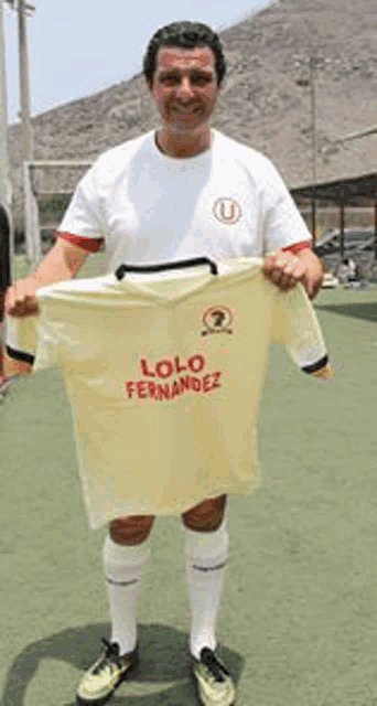 a man in a white shirt is holding a yellow shirt with the name lolo fernandez on it