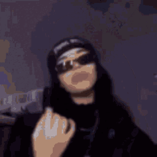 a blurry picture of a person wearing a hat and sunglasses .