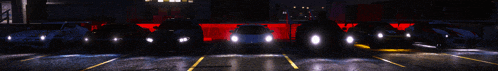 a row of cars parked in a parking lot at night