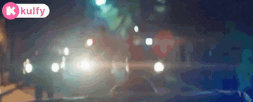a blurred image of a street at night with a k kulfy logo in the corner