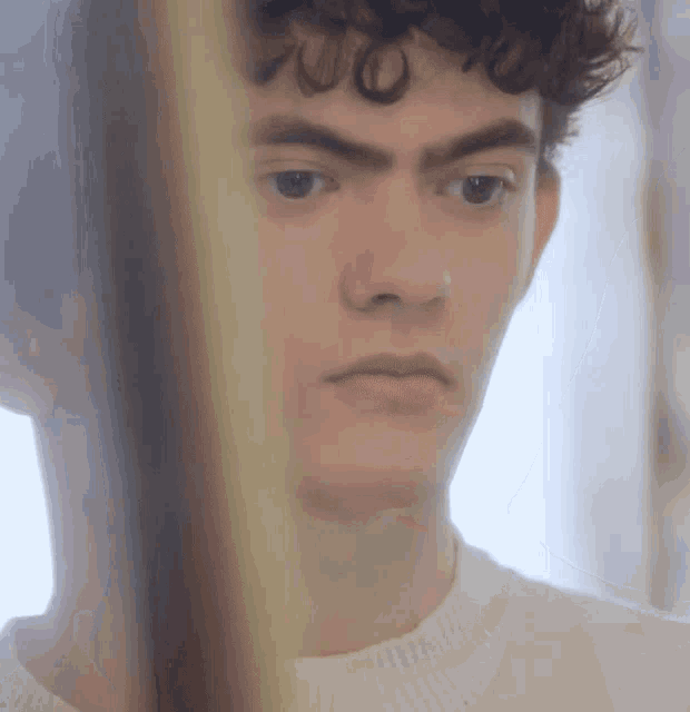 a man with curly hair looks at himself in a mirror