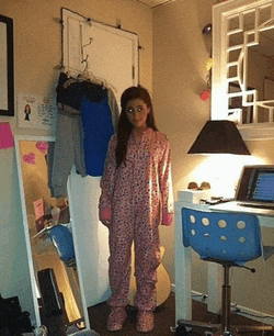 a girl in pajamas stands in front of a mirror in a room