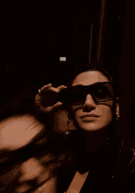 a woman wearing sunglasses is waving at the camera
