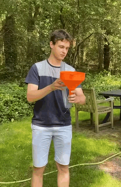 a young man is pouring water from an orange funnel into a hose