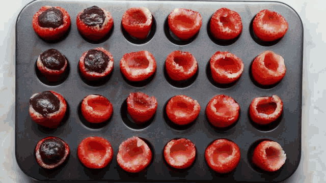 a muffin tin filled with strawberry cups filled with chocolate sauce
