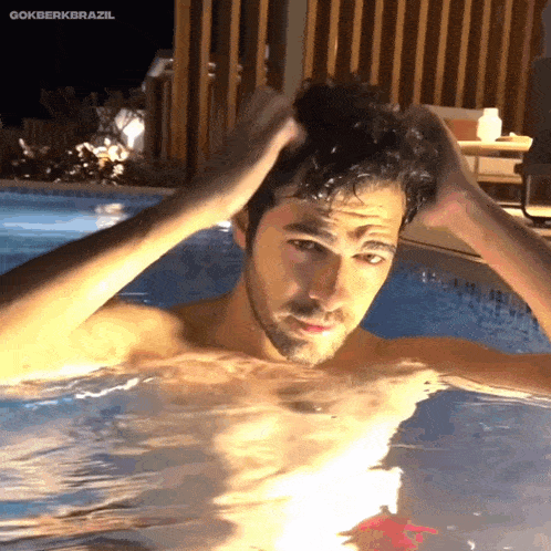 a shirtless man is swimming in a pool and the caption says gokberkbrazil
