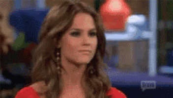 a woman in a red dress is sitting in front of a sign that says bravo on it .