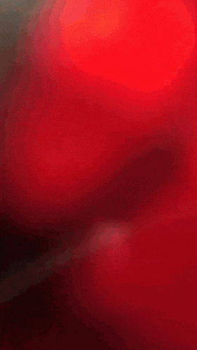 a blurry picture of a woman standing in front of a red object with the letter s on it