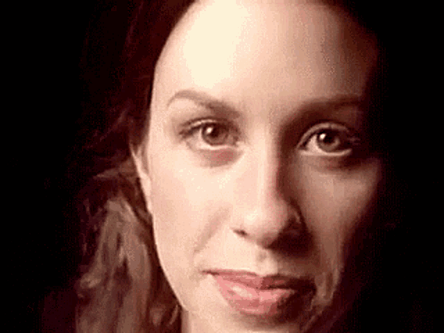 a close up of a woman 's face with a black background and a red lip .