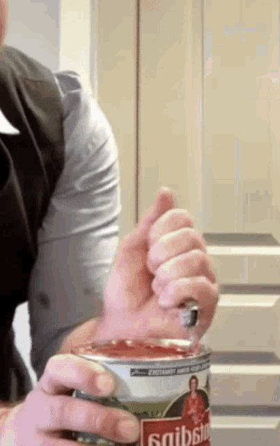 a man is opening a can of garibaldi sauce