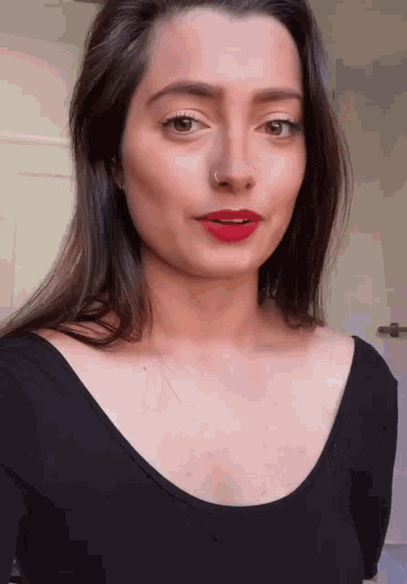 a woman with red lipstick and a nose ring is wearing a black top