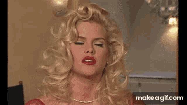 a woman with blonde hair and red lipstick is making a funny face .