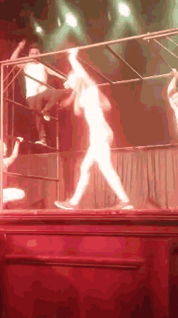 a woman is dancing on a stage with a red light behind her