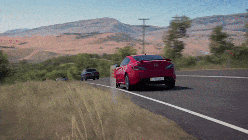 a red car is driving down a road with mountains in the background and a license plate that says jcl lgd