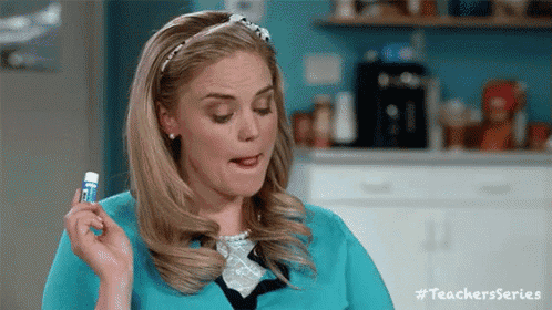 a woman in a blue shirt is holding a lip balm and making a funny face .