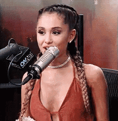 ariana grande is sitting in front of a microphone .