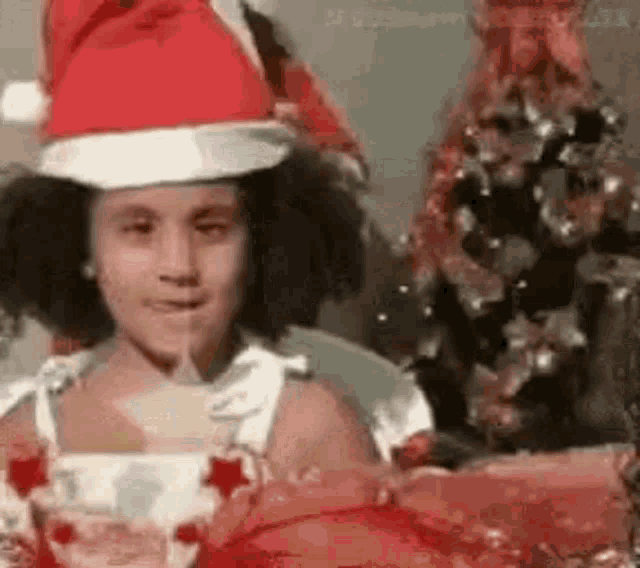 a little girl wearing a santa hat is sitting at a table .